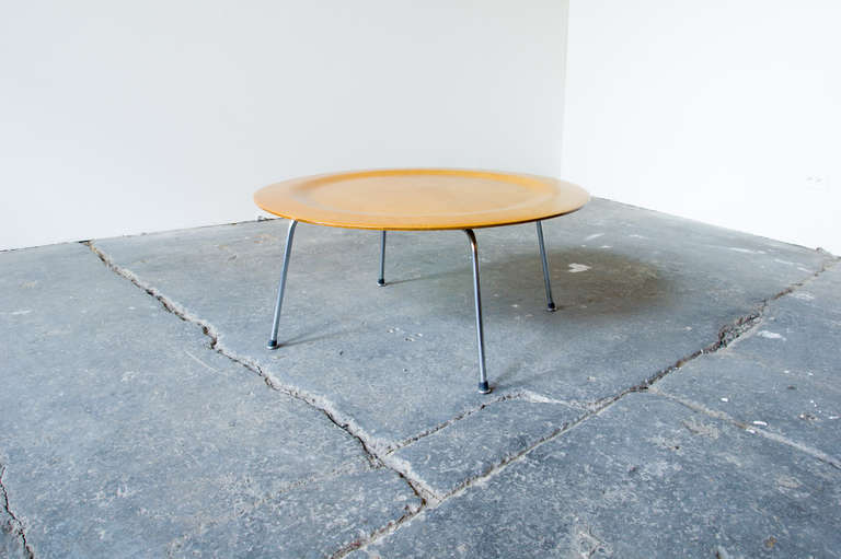 A second generation Eames CTM (coffee table with metal legs) in birch. This Classic design features a dimpled plywood top, which appears to float over its slim metal legs. This generation uses a black-painted wooden x-brace where the legs meet the