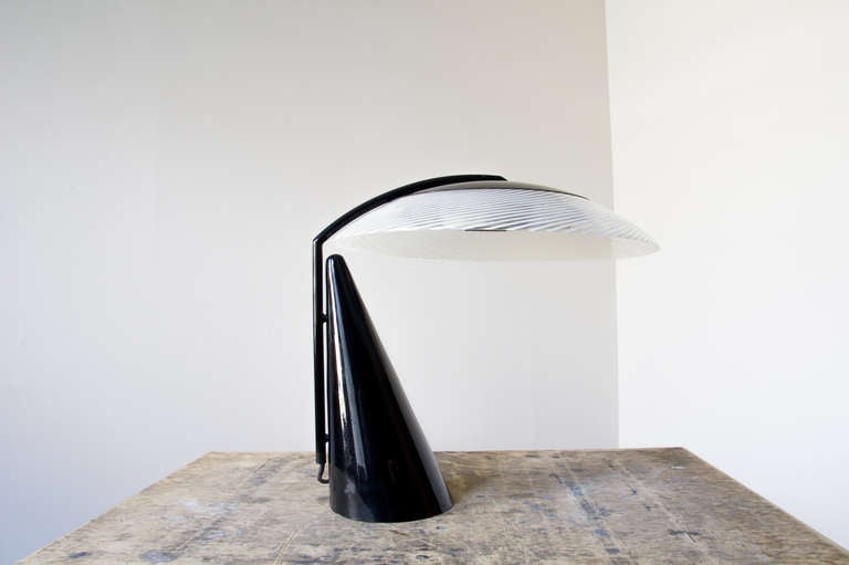 A mod Italian desk lamp with exquisite lines and exceptional construction. Its base is metal and substantially weighted. The shade is delicate glass with white striped detail.