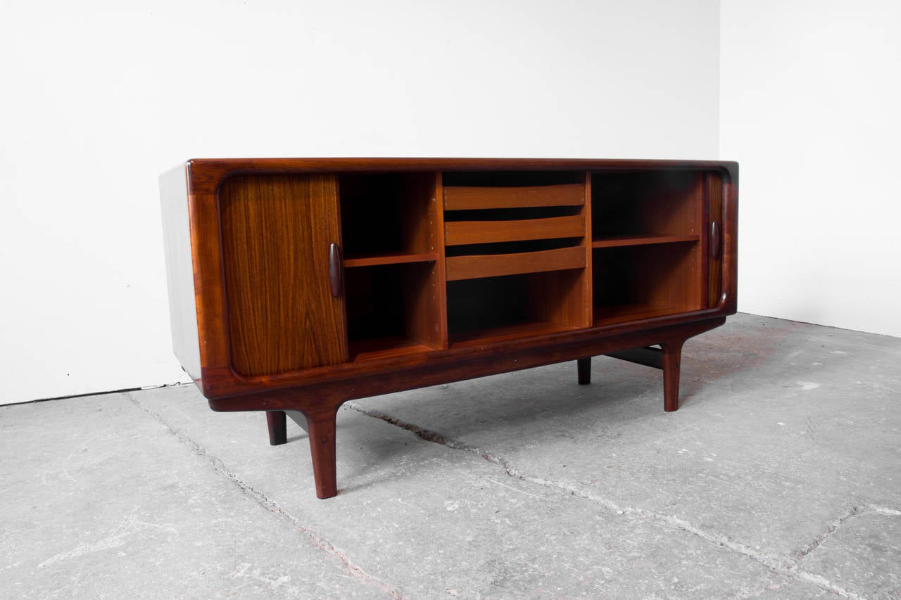Three drawers, two adjustable shelves, robust, sturdy, clean, figural, server, capped holes for wires.

A sinuous, clean lined tambour-door credenza or server by Dyrlund with highly figural rosewood veneer. It sits low and wide, providing