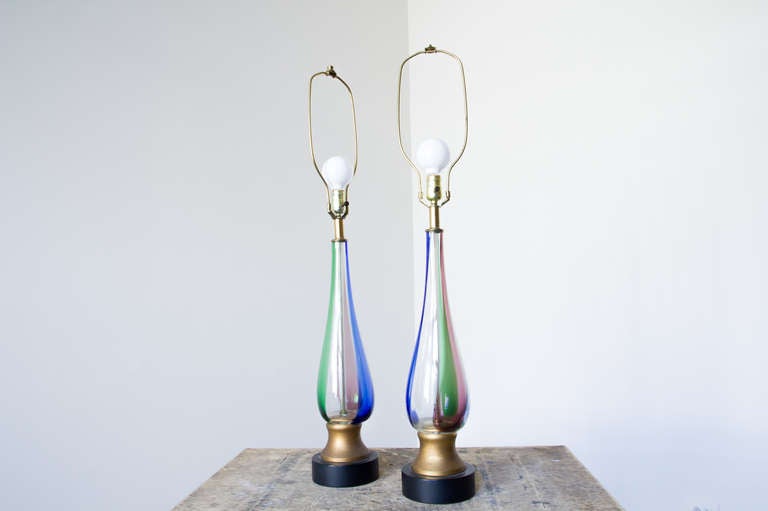 A pair of colored glass tulip form Murano lamps. Green, pink, blue and green panels wraparound the ascending taper which is given an airiness with the ability to see inside the form. In the manner of Venini.