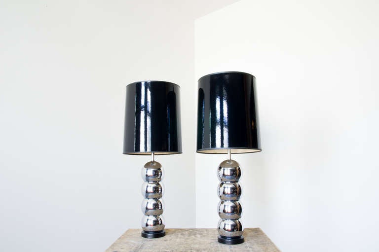 A pair of chrome lamps by Laurel with a repeating ball pattern on a black base. The pair is complete with their original black shades which have a reflectivity similar to that of the chrome.