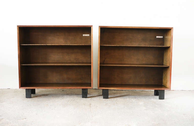 A set of classic George Nelson bookcases in walnut with two adjustable interior shelves and finished on black lacquer feet.