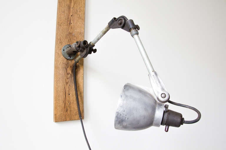 A wall or desk mountable adjustable task lamp by Woodward Machine Co. The shade swivels; the halfway point of the arm pivots, and at the base the fixture can extend or retract in reach.