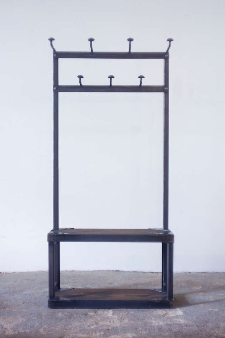 This Strawser & Smith original coat rack bench features patinated steel slats on the seat and lower shelf, both of reclaimed wood. The iron coat hooks were salvaged from a turn of the century schoolhouse.