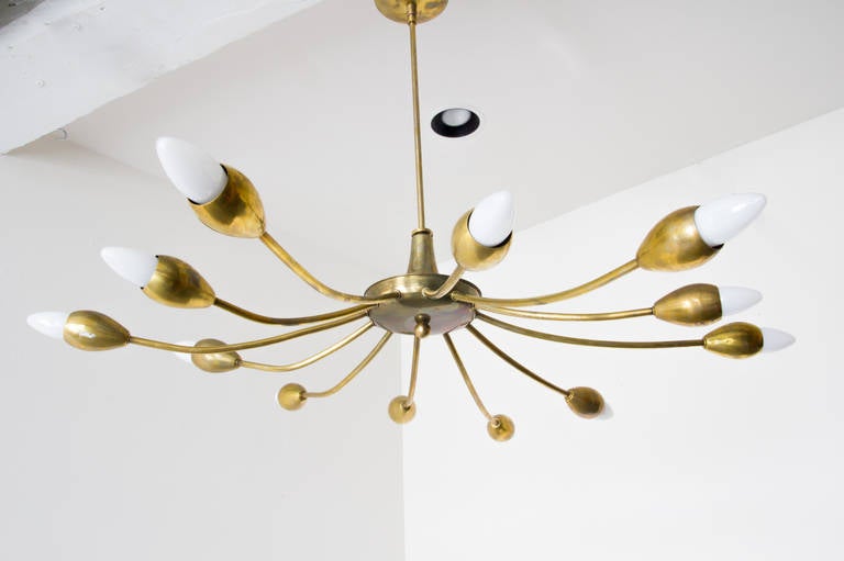 An elegant brass Sputnik fixture in the Stilnovo style with twelve spokes. It throws light in an evenly wide pattern, and is as attractive unlit as it is lit. The brass is thick all around, and all original hardware has been retained.