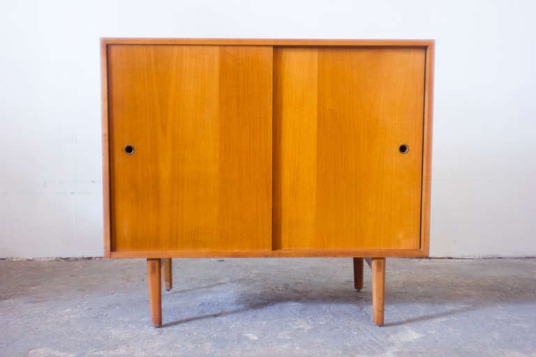 This birch media console, by Paul McCobb for the Planner Group, features two sliding doors and a single shelf within. As can be seen in the photograph, it has the original tag located on the backside.