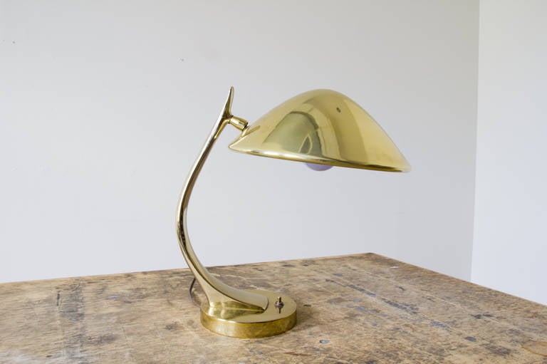 A petite sculptural brass lamp by Maurizio Tempestini for Laurel. A push button turns the lamp on and off situated at the base. The solid brass stem reaches upward in a curved form where the shade is attached on a ball and socket joint. The head