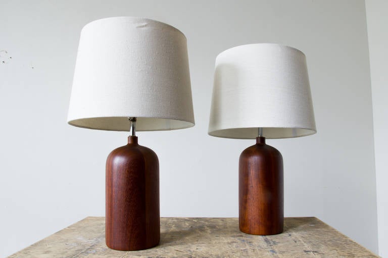 A pair of Danish lamps in teak. The off-white shades compliment the wood and vice-versa. The body is well weighted for stability.