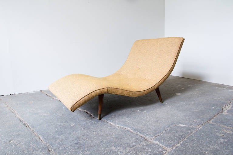 A highly styled, organic wave chaise by Adrian Pearsall for Craft Associates. Thin padding makes for a particularly exaggerated wave-form, without the sacrifice of comfort. Subtly patterned beige upholstery compliments the wood. Brass tacks along