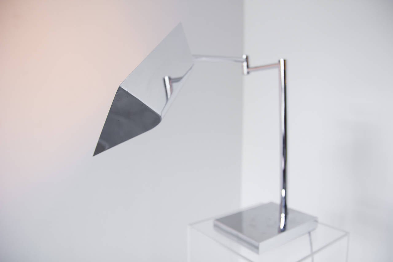 Una elegante lámpara de escritorio en cromo pulido de Koch & Lowy; la pantalla de la tienda se articula sobre una rótula y se ajusta además sobre un brazo oscilante.