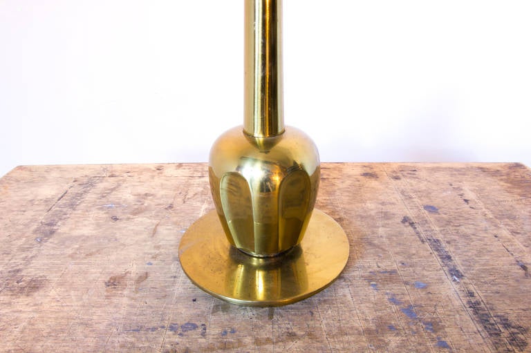 A solid brass table lamp by Stiffel on a circular brass base plate. The bulbous form ascending from the base features thumbprint impressions all around. The thin stem tapers off until it meets a smaller brass plate, just before the bulb.