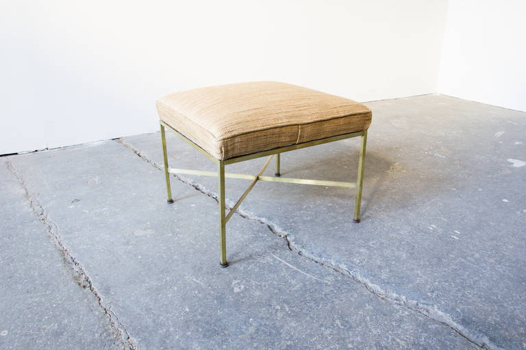 An elegant stool by Paul McCobb for Calvin in brass and upholstery. Thin, ribbon brass stretchers connect squared brass legs. It is low, and multifunctional in the home.