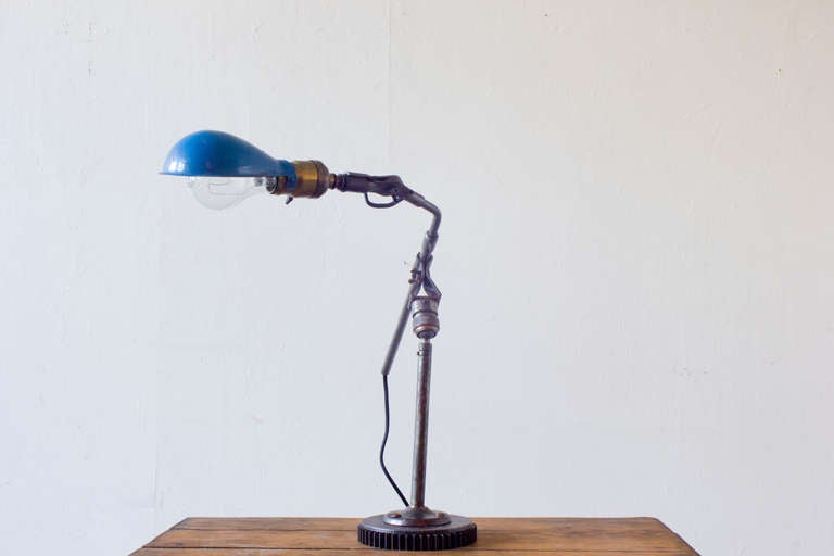 This handy lamp is endlessly adjustable for just the proper angle. We have modified it to sit on a substantial vintage gear base. The rotating shade is blue enamel.