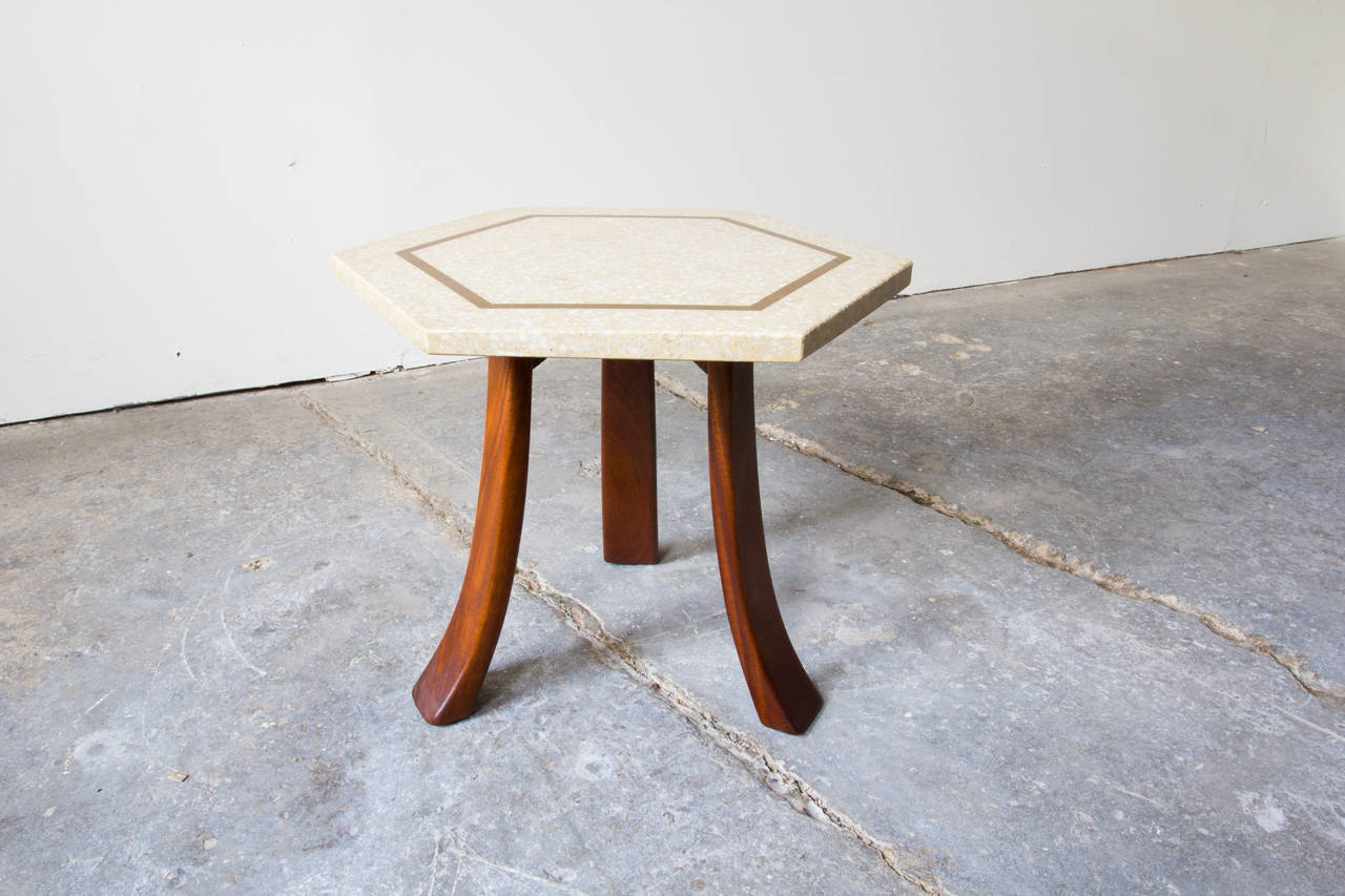 A rare three-legged hexagonal side table by Harvey Probber. The heavy terrazzo top is supported by three bent mahogany legs. Brass inlay, inset from the edges of the tabletop, accentuates the hexagonal shape and completes the marriage of three