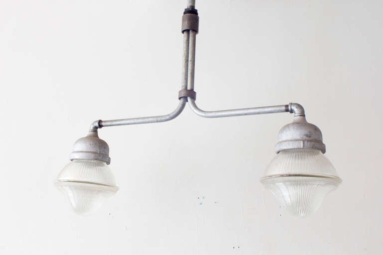 An Industrial dual light fixture of steel and robust Holophane glass.
