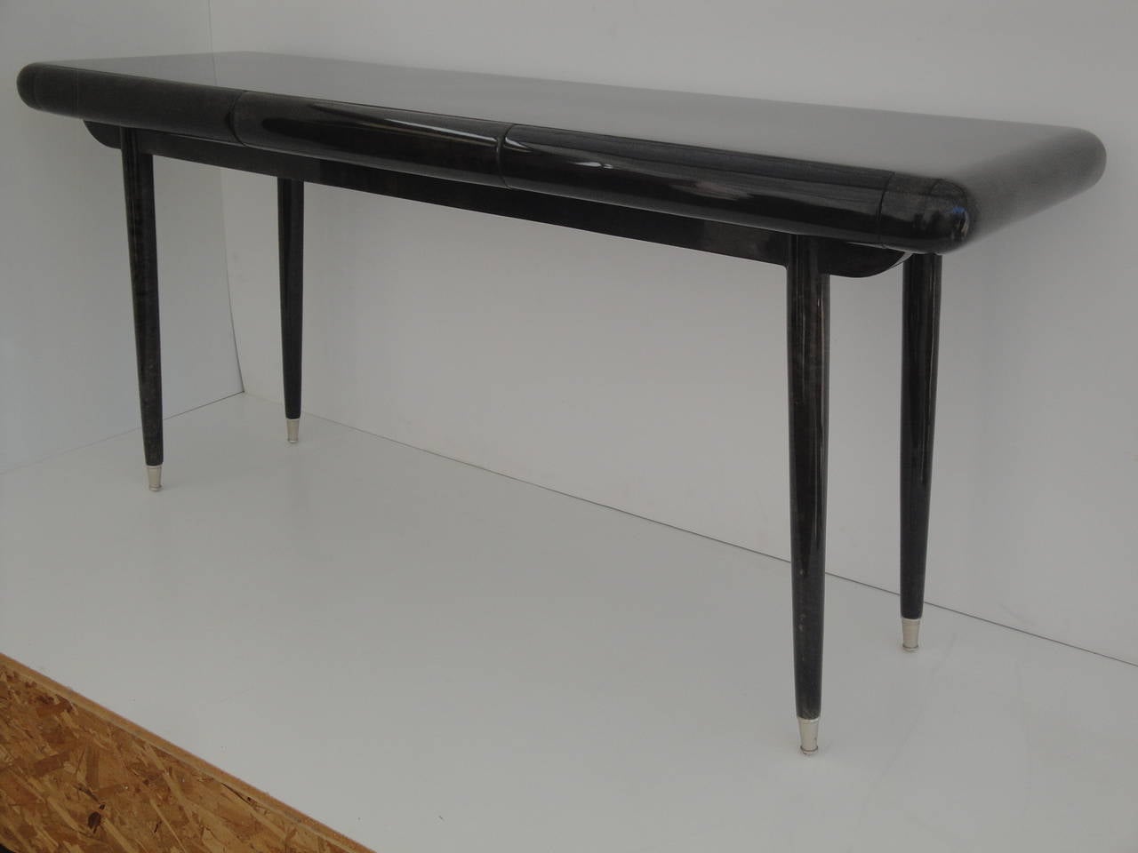 Charcoal gray parchment console table in the style of Karl Springer with three bullnose drawers.
