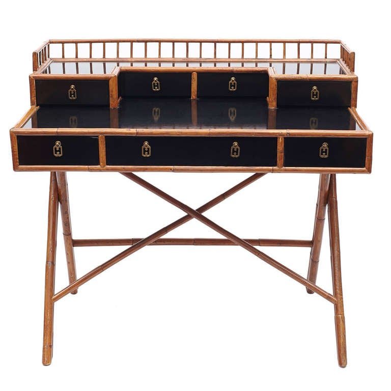 A desk with black lacquered case and bamboo legs, edging and gallery; comprising seven drawers with chinoiserie style brass pulls. Stamped to the interior drawer 