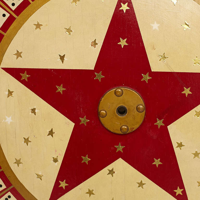 A unique game wheel painted red, cream and gold, and decorated with gold stars and dice.  American, ca 1940s.

Good vintage condition.
