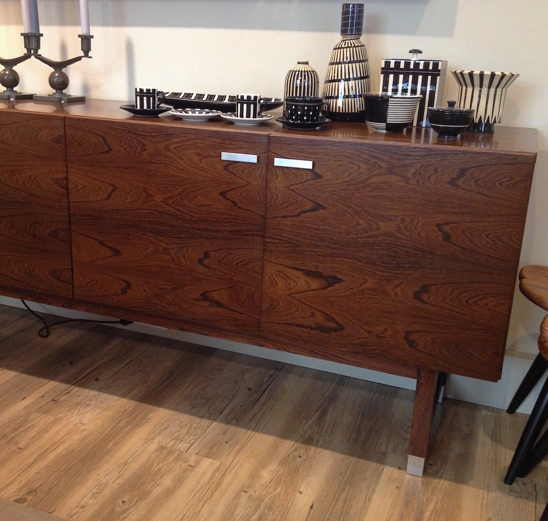 Low sideboard veneered with rosewood, front with four doors with magnets, shelves and pull-out tray, grips and shoes polished aluminum. Some restoration was done to the piece to eliminate lighter areas. It is now in excellent condition.
Measures: H