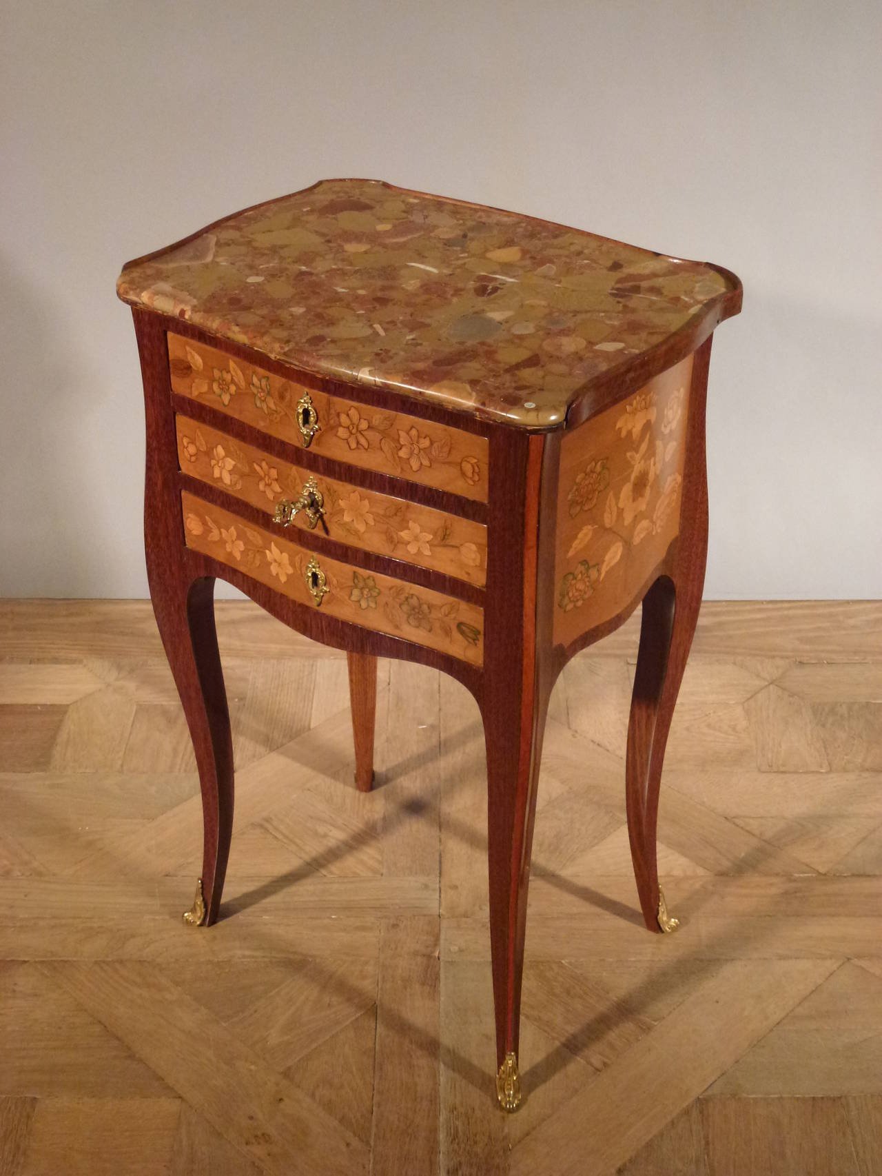 This elegant table has a rectangular moulded brèche d'Alep marble top in a three-quarter gallery above three drawers inlaid with flowers-sprays. The upper drawer contains a green leather writing surface. Both sides are inlaid with scroll  flower