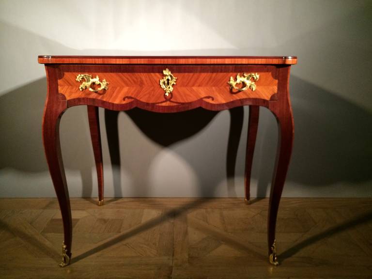 Rectangular shaped top, frieze drawer with gilt bronze mounts, decorated with marquetry of scrolling guirlandes, on high slightly bent legs with gilt bronze mounts and sabots.

Provenance: Formerly in the collection of Baron van