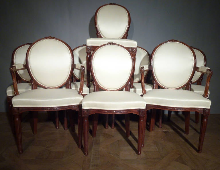 Comprising a pair of open armchairs and six side chairs, each with channelled curved oval back and bow-fronted seat, the toprail centred by a ribbon-tie, the arms with Greek key terminals and curved supports, the seat-rail carved with bead-and-reed,