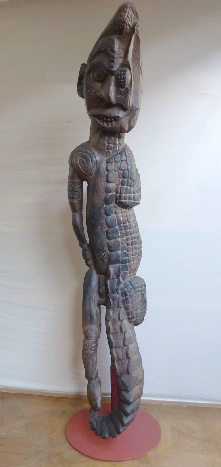 Carved as half a man, half a crocodile, from the Sepik river area in Papua New Guinea. Carved wood with black pigments on a modern iron stand.

Life in the Sepik area revolves around the river. The Sepik is a gallery of tribal art, each village