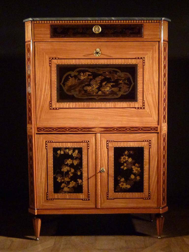 This 'secrétaire à abattant', with a grey marble top, is modelled with one drawer above a fall-front, enclosing a fitted interior and two cupboard-doors below. The fall-front is inlaid with a large lacquer panel with birds, flowers and clouds