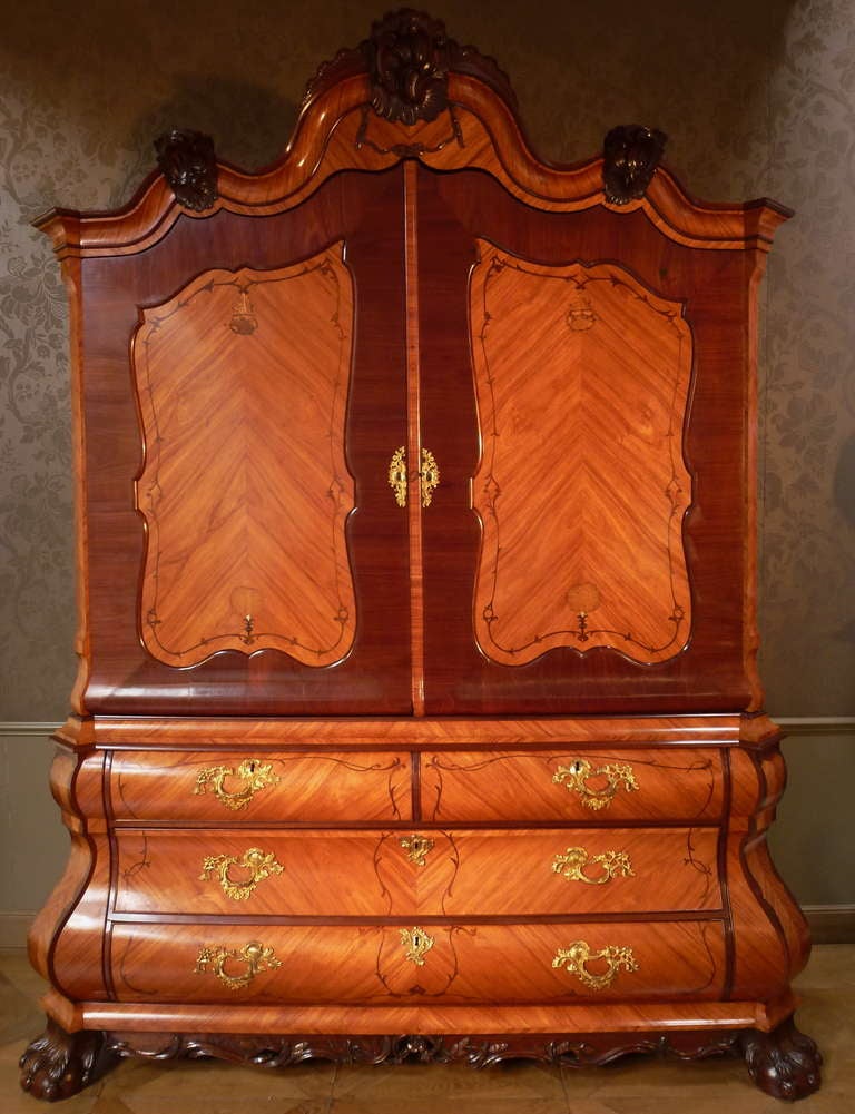 The double bent upperpart with two cupboard doors, each with a marqueterie of two flowers and initials, the inside fitted with a smaller shelf, a large shelf and three drawers. The lower part with two smaller and two larger drawers, the opening