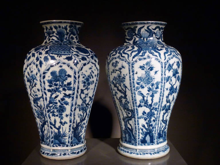 The octagonal baluster-shaped vases on footrim, spreading foot with moulded plint, decorated in underglaze blue; the body with eight panels enclosing flowering branches and birds within borders of flowers and foliage, on the shoulder and neck