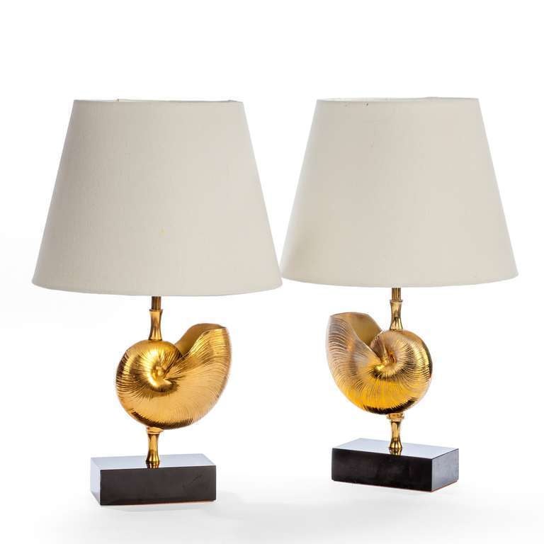 Pair of bronze table lamps sitting on black marble bases in the shape of a nautilus shell.