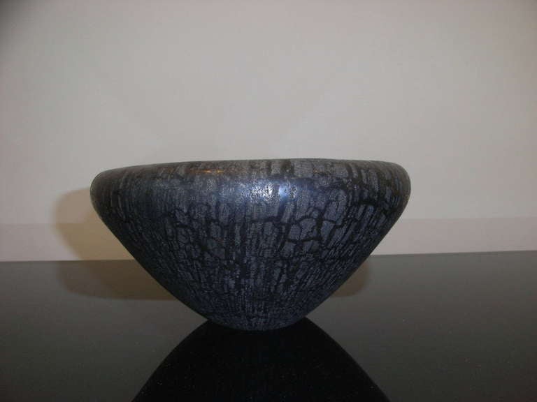 Black glass bowl using the Scavo technique.

The Scavo technique was introduced in the 1950s by Alfredo Barbini and was designed to imitate the effect caused by long periods spent underground, typical of glass objects found during archaeological