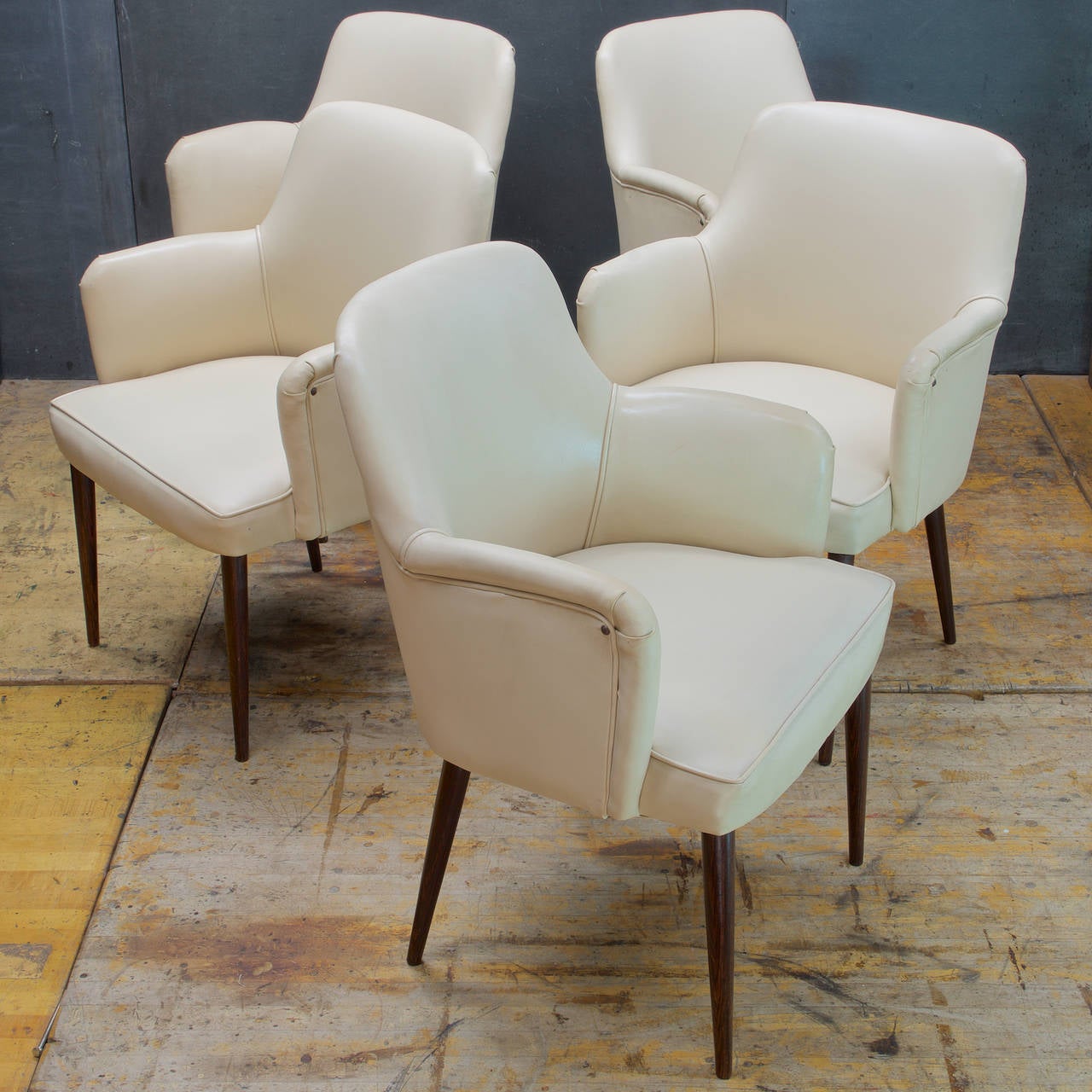 Set of Four, and the fifth one is Free.

Hardwood Pencil-Leg Dining Armchairs, Wood Grain looks like Rosewood or Wenge.  In Original Off-White Vinyl Upholstery. These are Presented in As-Found Condition, however these chairs are Useable and