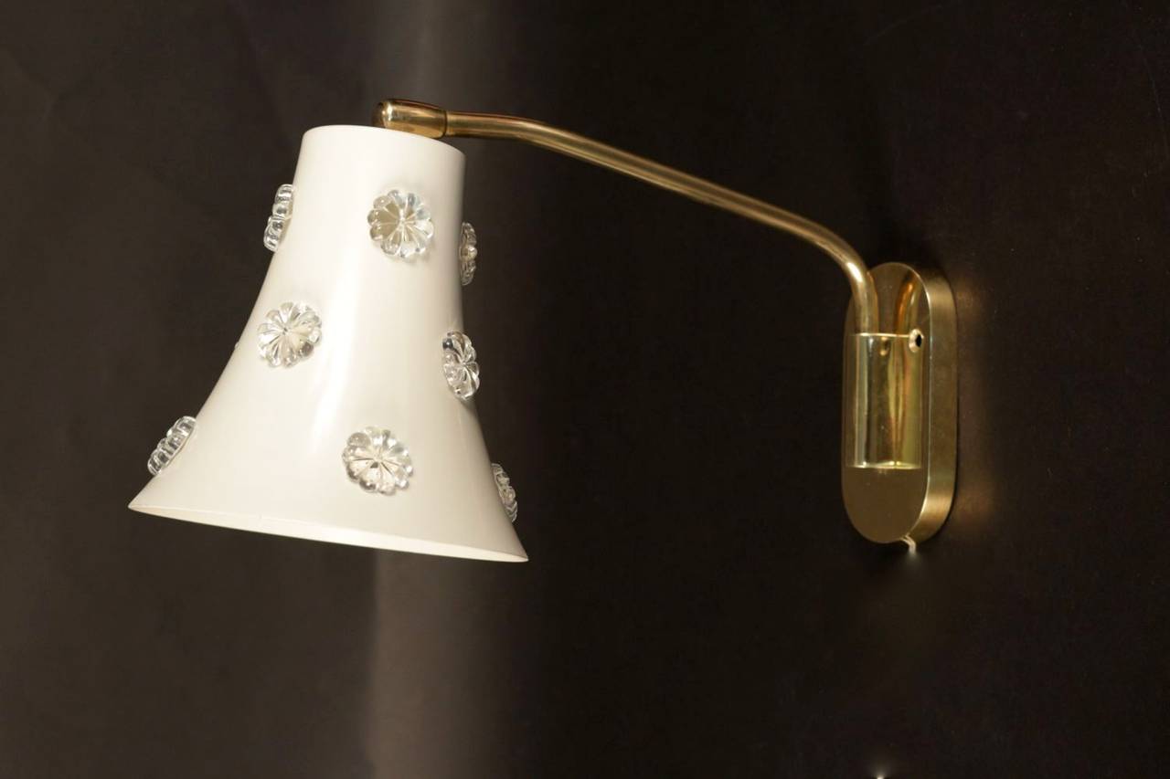 Pair of 1950s 'Daisies' sconces attributed to Maison Stilnovo in cream color steel sheet decorated with small translucent glass flowers. The base of the lampshade is mounted on ball joint and the rod is adjustable. The base and the rod are in brass.