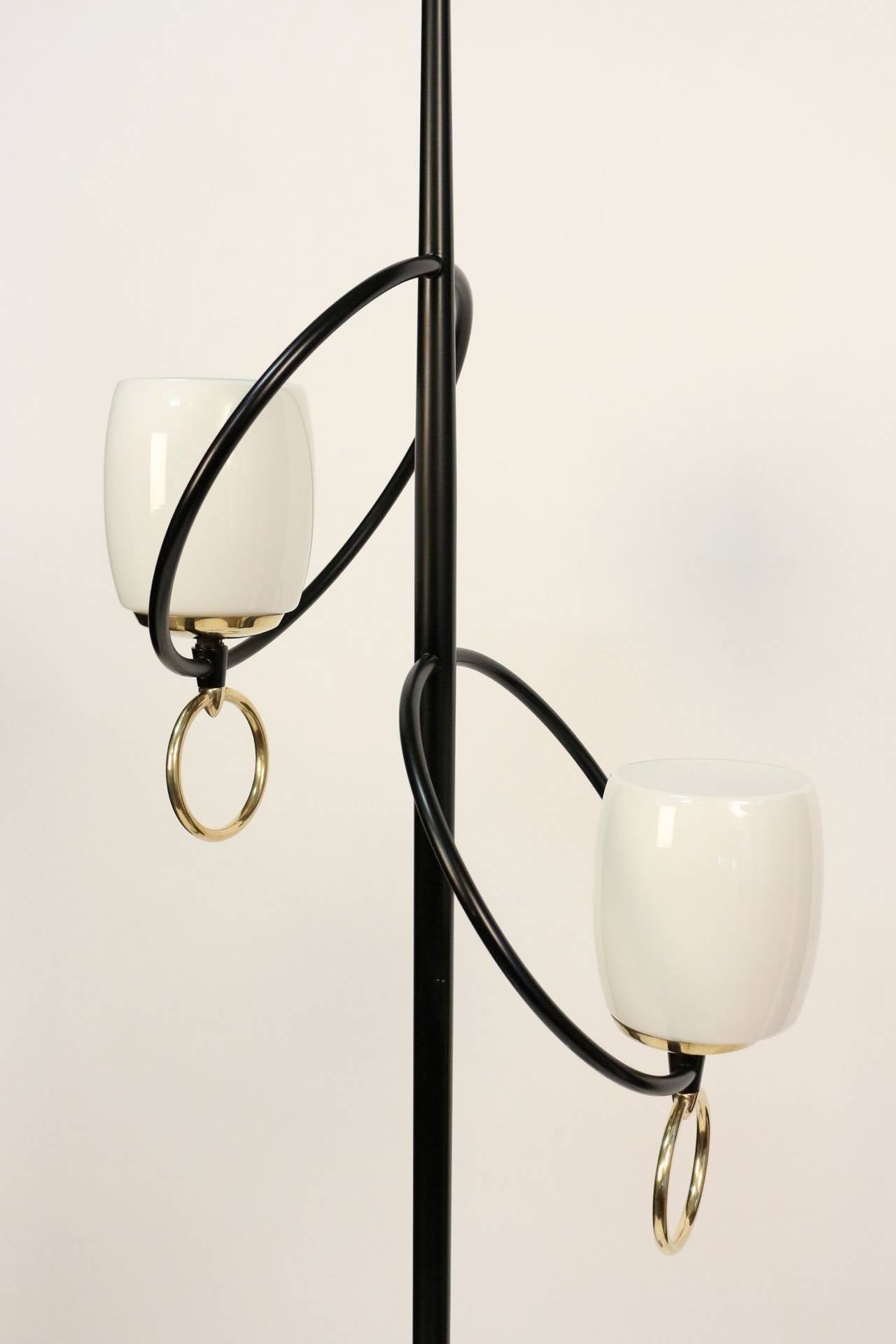 1950s 'buckle' floor lamp by Stilnovo in gilt and blackened brass. Closed white opaline shade highlighted with two brass buckles, the top of the trunk underlined with a touch of gilt brass.
Two lights.