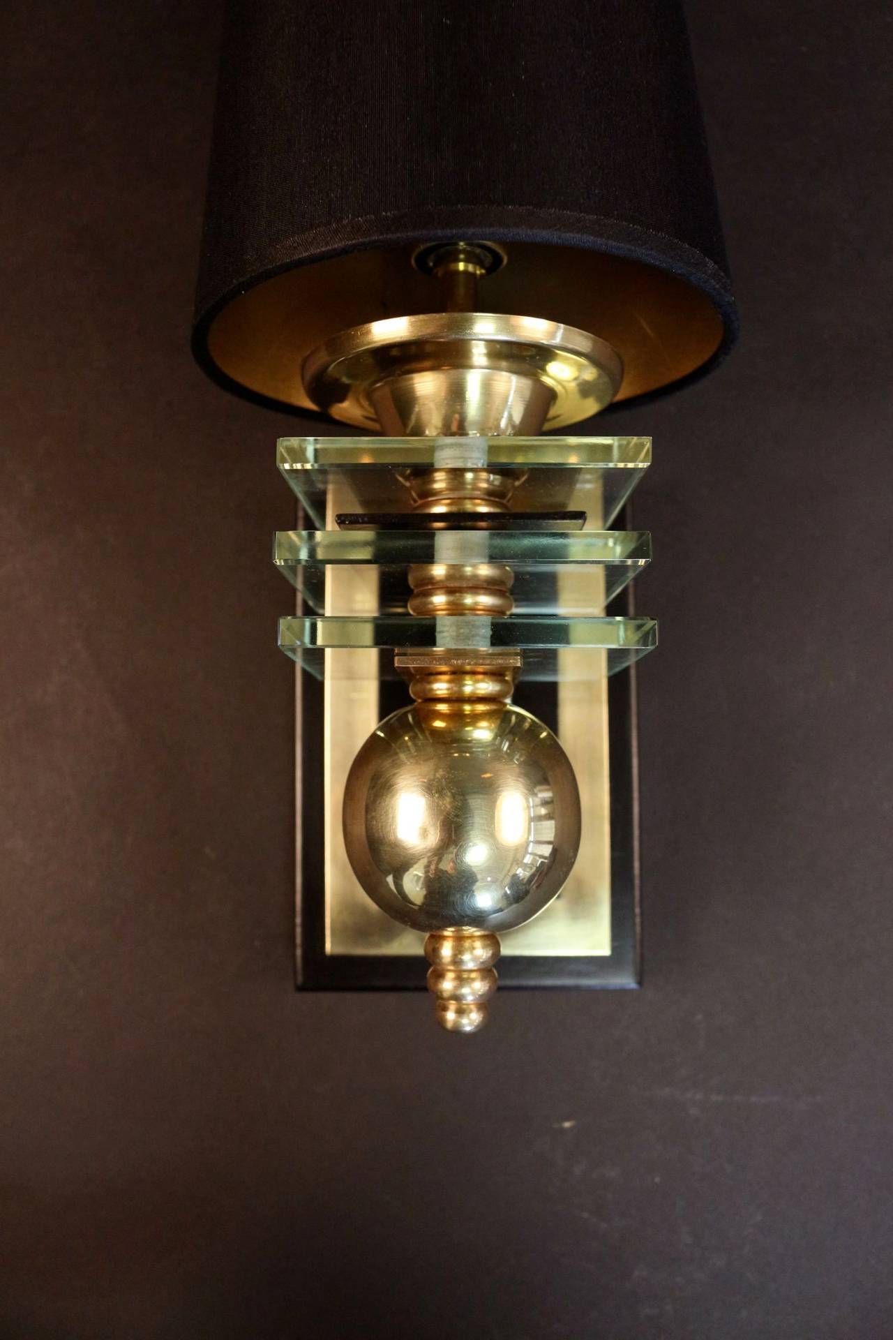 Pair of 1940s sconces by Maison Petitot in gilded and blackened brass. The trunk base is made of three glass plates decorated with inlined brass balls. New black custom lamp shade.