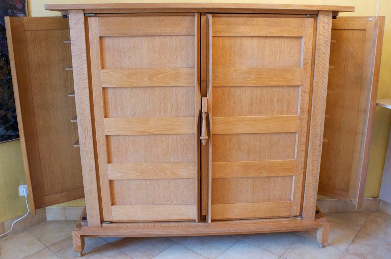 Rare 1950s Guillerme et Chambron 'Bouvine' dress.
In solid oak with two front doors opening on a set of adjustable shelves. 
The sides are adorned with doors opening on set of shelves. Brass hinges.