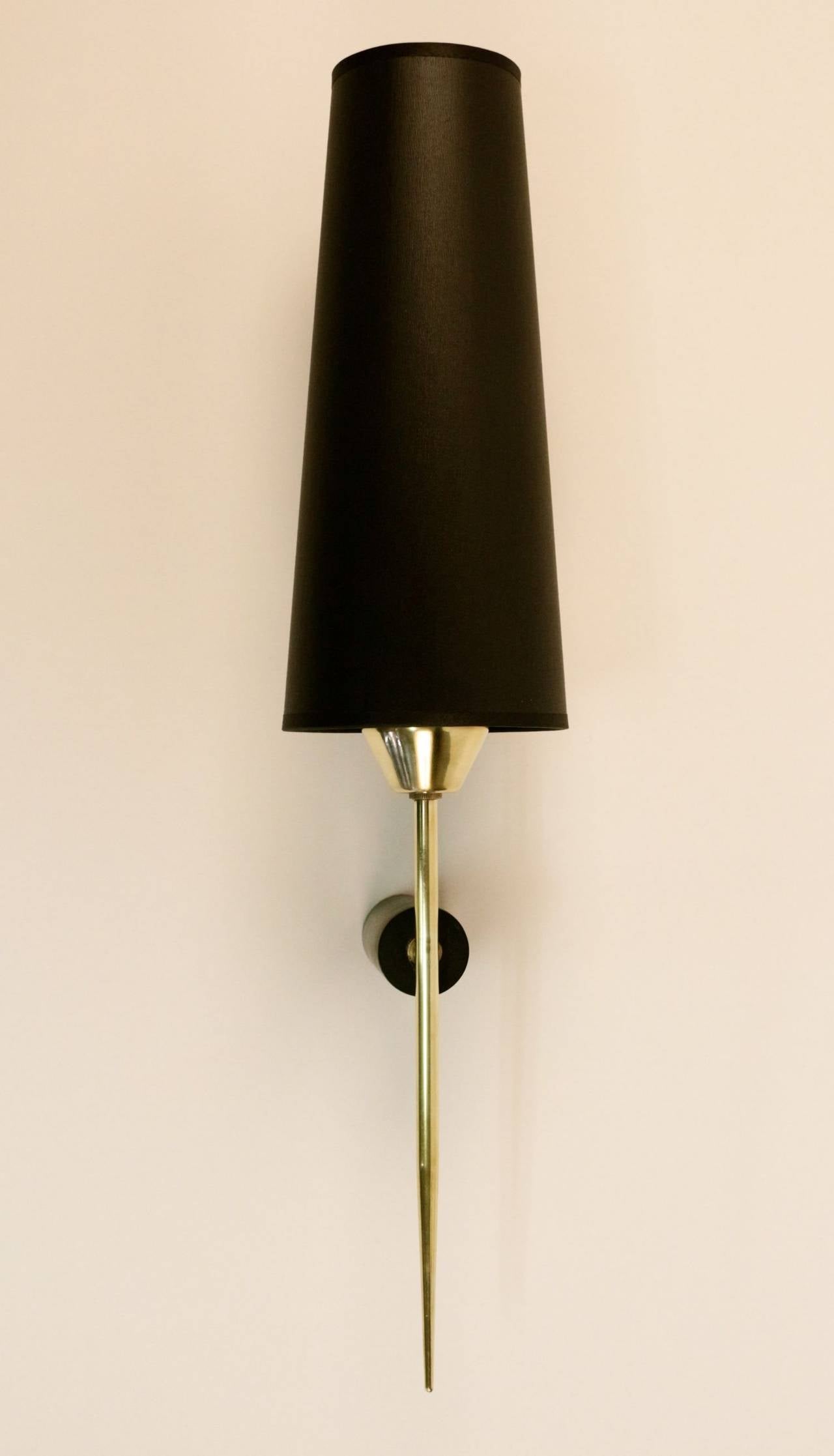 Large pair of 1970s flare sconces by Maison Lunel.
Gilt brass rod enhanced by a blackened cylindrical brass support. One-lighted arm per sconce, gold color inside and black outside lampshade.