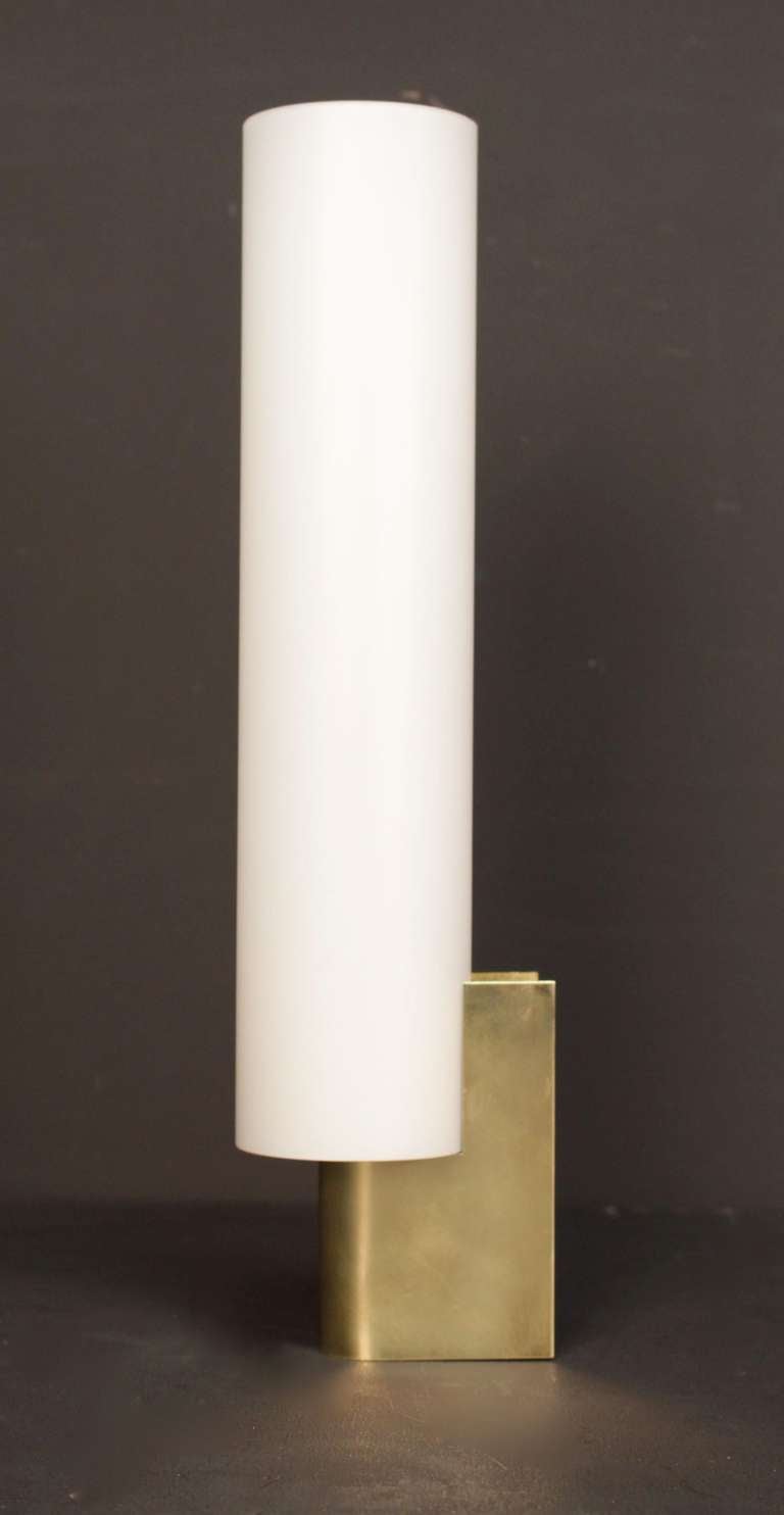 Set of three Maison Lunel Sonces. Curved brass base. One lighted arm per sconce. Opalin cylindrical shades.