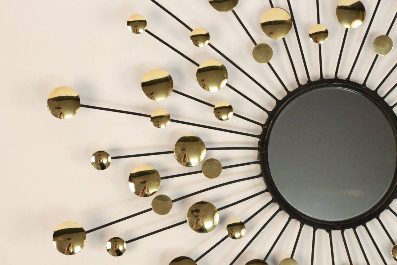 1950s eccentric wall mirror by Chaty Vallauris.
The fixture and the sun beams are in wrought iron. They are enhanced by gilt brass circles of random dimension. Original mirror.