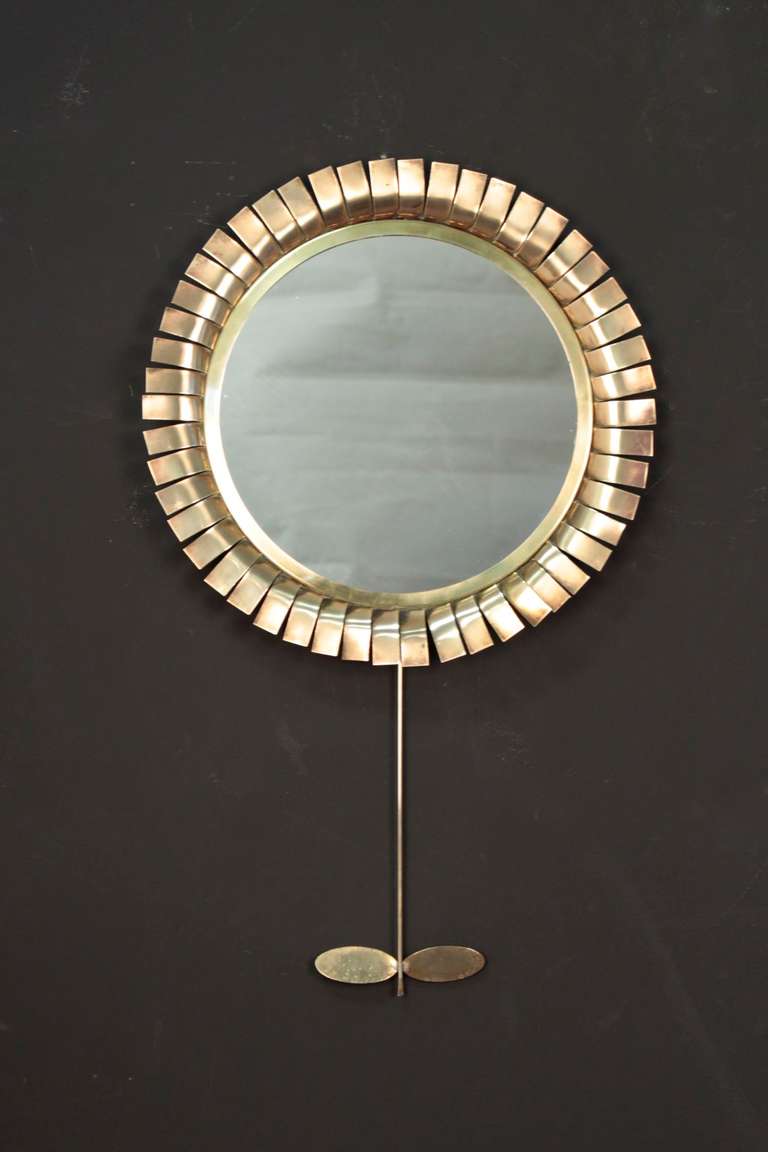 1970s daisy mirror attributed to Jere Curtis and framed with brass petals. the stem adorned with two brass leaves. The back of the mirror is covered with black velvet.