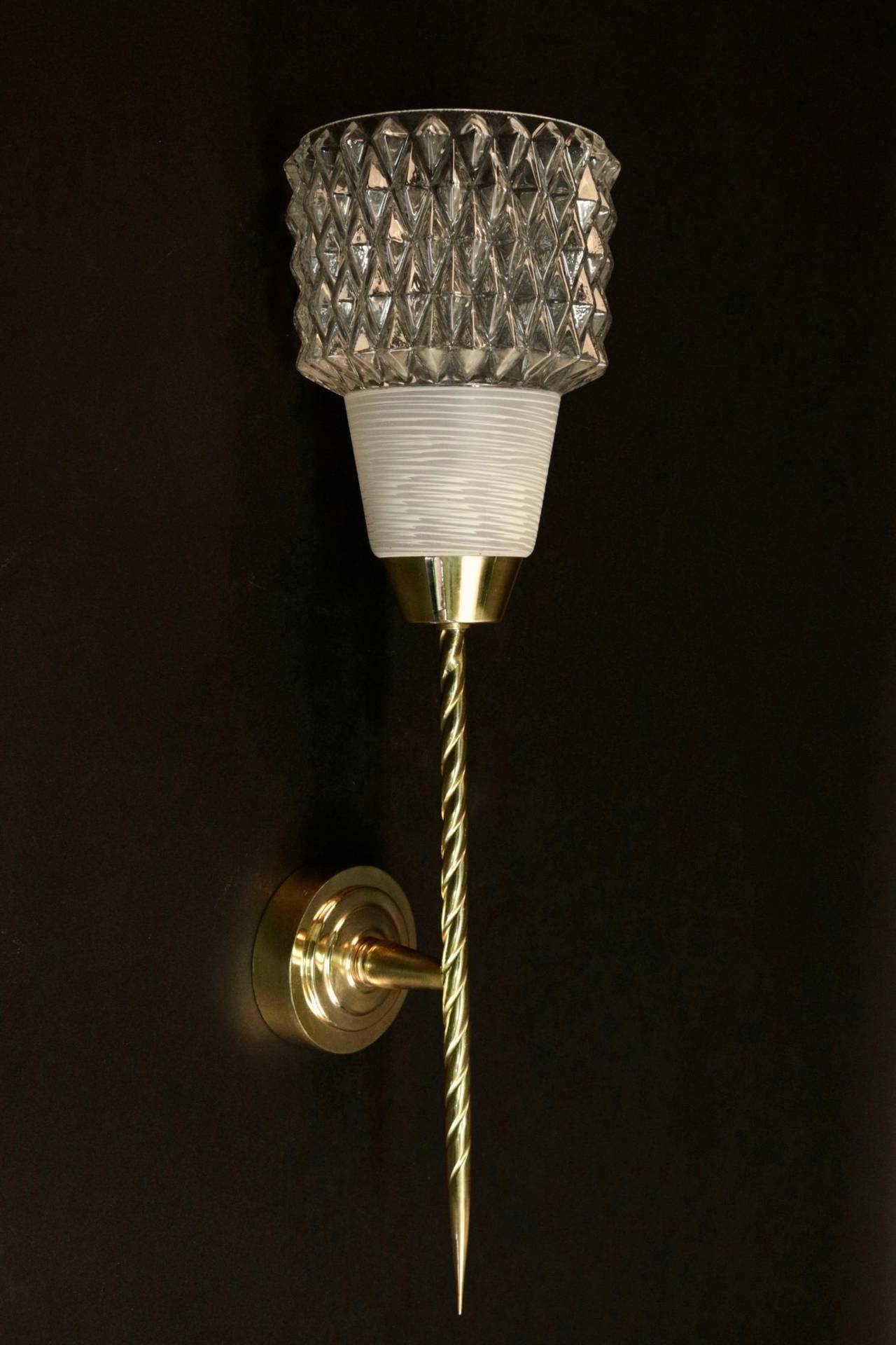 Pair of 1950s flare sconces by Maison Arlus.
Composed of a twisted brass rod enhanced by a glass cup which is diamond shaped on its upper part and soft and mate on its lower part.
One lighted arm per sconce.