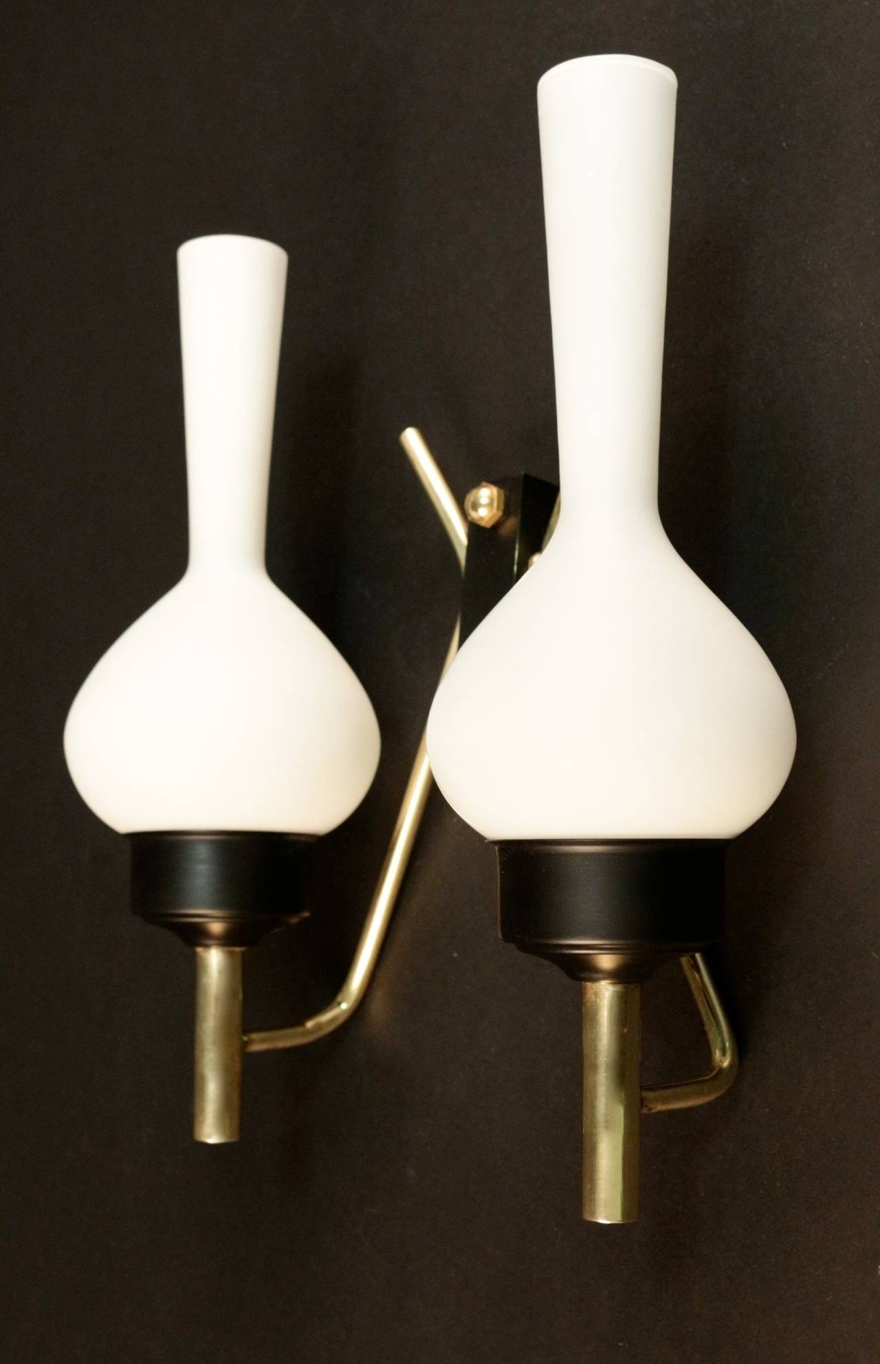 Pair of 1950s 'Spinning Top' sconces attributed to Stilnovo. 
Composed of two brass lighted arms fixed on a backplate decorated with a brass ball. 
Two original spinning top shape lampshades per sconce.