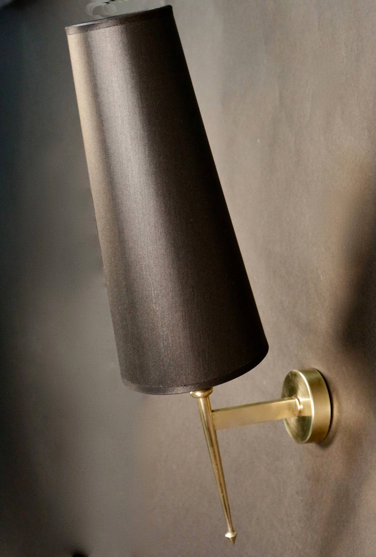 Pair of 1950s sconces by Maison Lunel. Brass rod with a pike end enhanced by a metal grey cup and topped with a tailored lampshade with gold inside and black outside. One lighted arm per sconce.