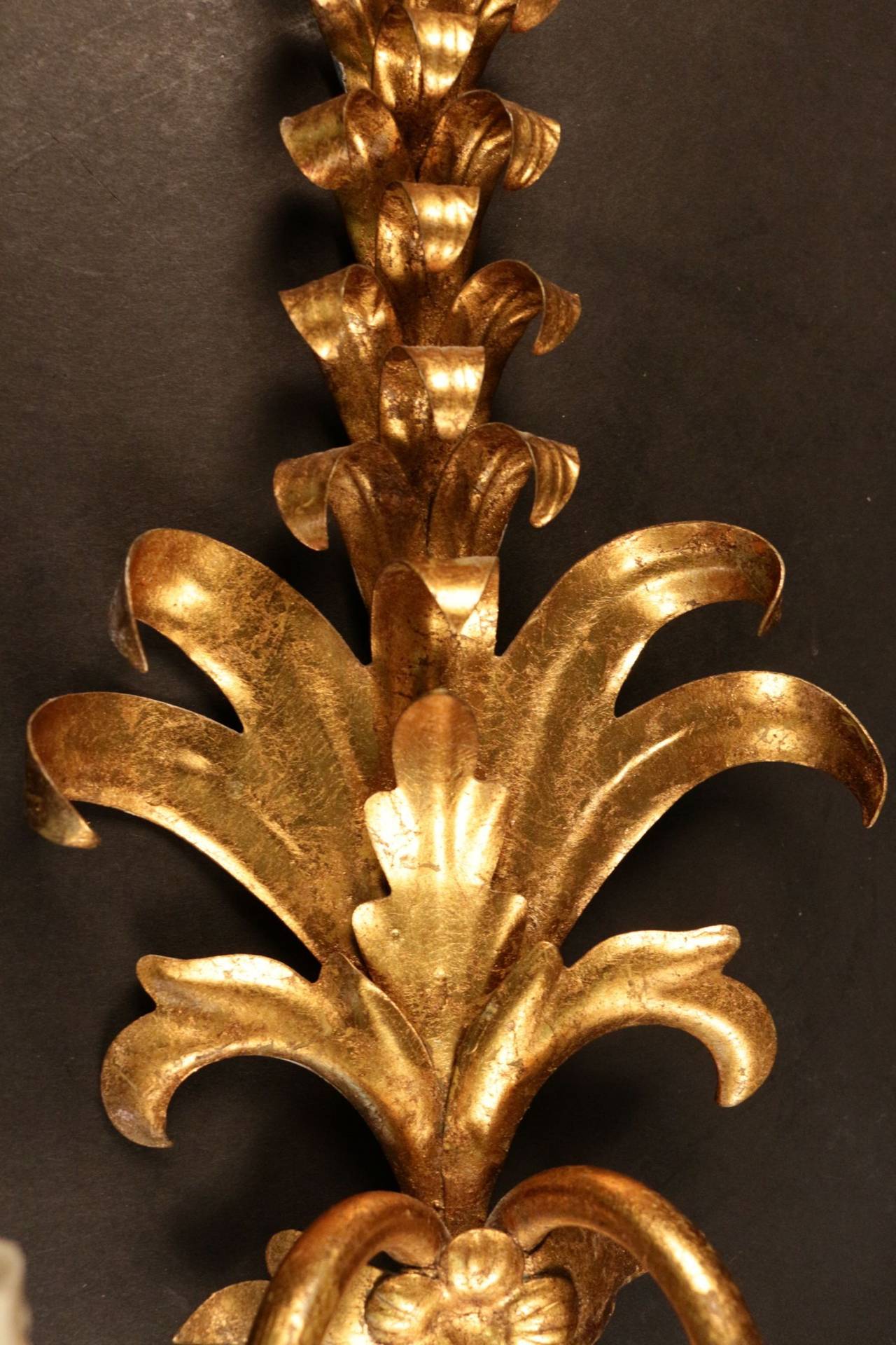 Pair of 1970s 'plant' sconces by Maison FlorArt. The center trunk 

The central shaft has a foliage decoration composed of small petals on the top and larger leaves on the bottom out of flowers and ribbons.
Decorated with two gilded iron lighted