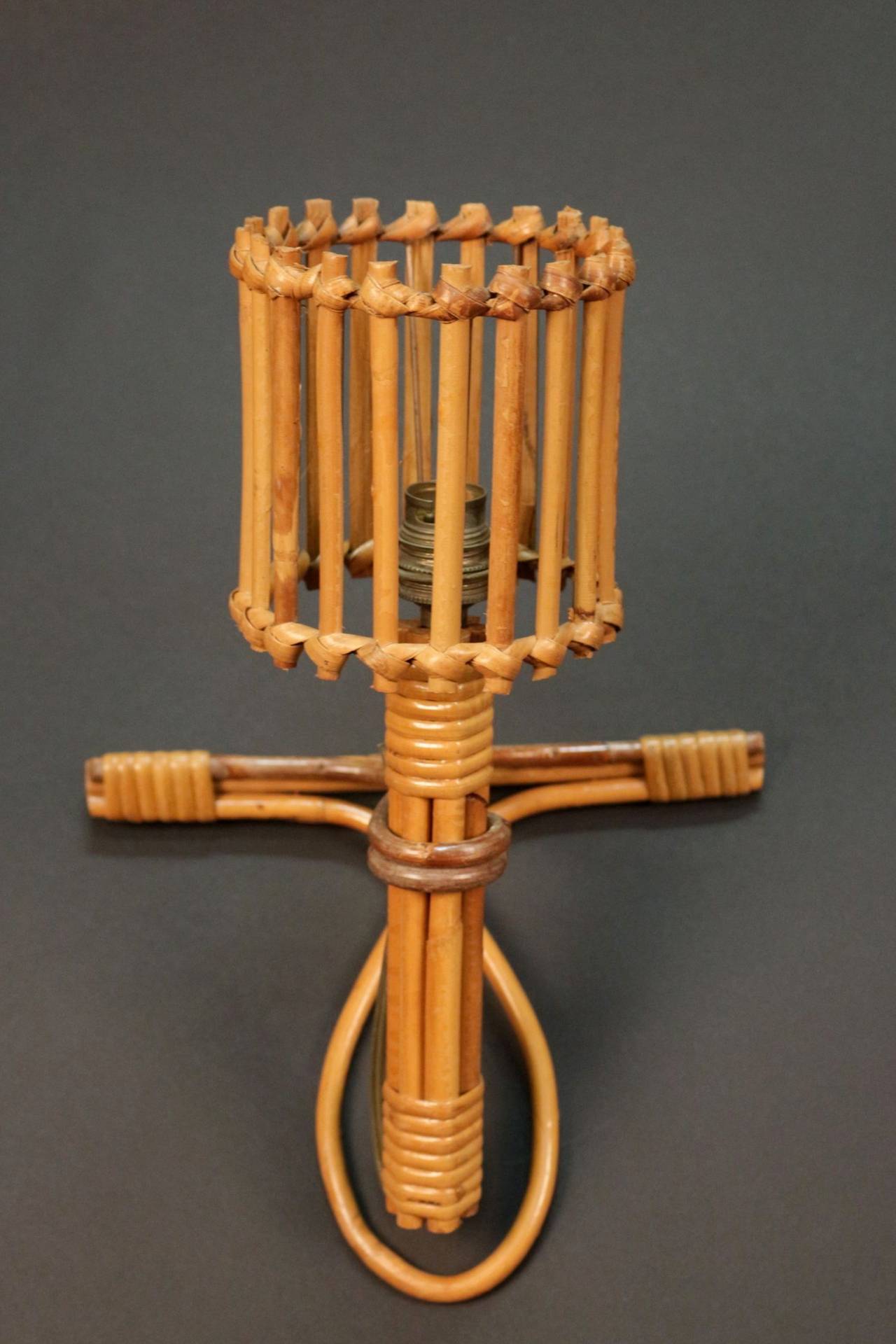 Pair of 1950s 'Bird Cage' rattan sconces. One lighted arm surrounded by a rattan cage. Each sconce is outlined by a rattan knot.