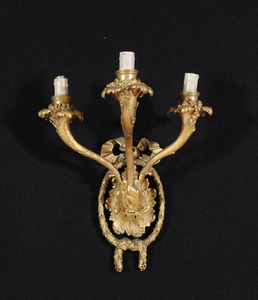 Four French 19th century gilt bronze three-light appliques, scrolling arms with acanthus leaves terminating in a corolla with a garland and knotted drap.
Measure: Cm 40 x 33 x 20.