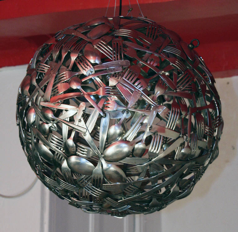 Stately spherical chandelier, made of silver plated metal cutlery assembled together. This unique and original art work has been realized by a French-Portuguese artist called José Esteves in the 2000s.  As well as being an art piece, this chandelier