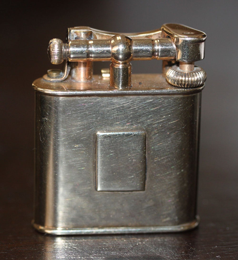 A Dunhill 9K Gold Petrol Pocket Lighter 

This Dunhill case was made in 1925 by La National, Paris, which was a French wholesale jewelry manufacturer
 
The case was sold to Dunhill as a blank and Dunhill used the blank and others like it to