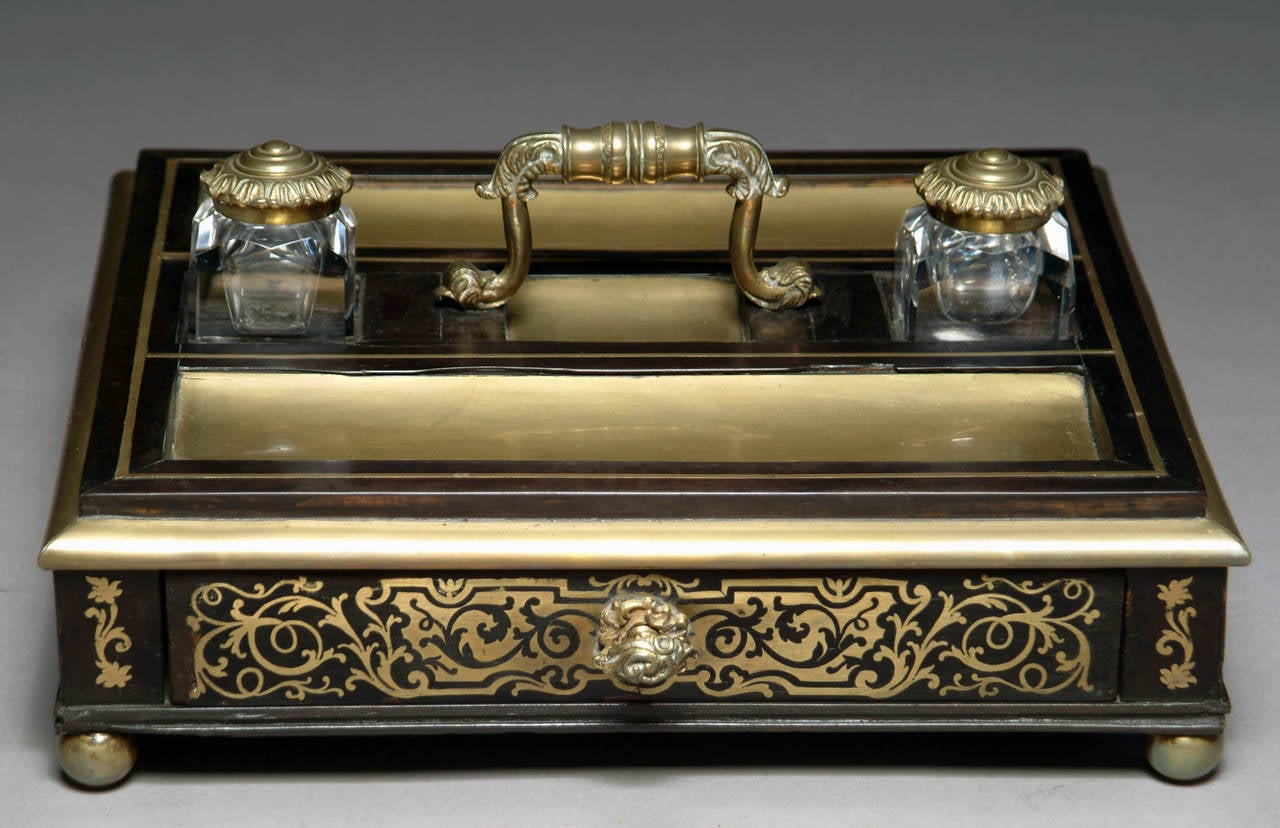 Circa 1900
 
Origin: Paris
 
Height: 3″ (7.5cm)
Width: 12″ (30cm)
Depth: 12″ (30cm)
 
Technique: Boulle
 
Having a Drawer, under two crystal ink holders with a centered handle